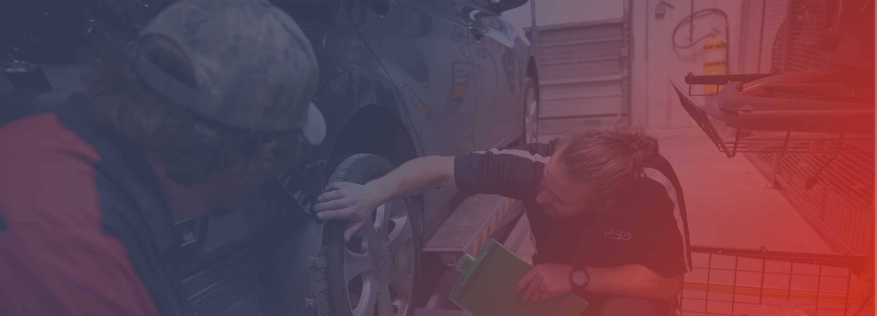 two repair technicians looking at vehicle in body shop